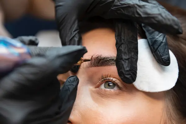 Woman getting her eyebrows microbladed with hairstrokes